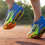 Gros plan sur un coureur portant des chaussures de running aux couleurs vives sur une piste d'athlétisme.